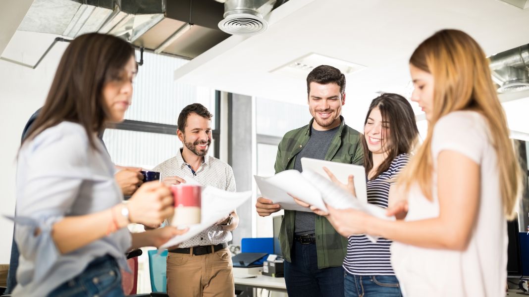 Colaboradores motivados en una reunión de negocios, alineando el aprendizaje de inglés con sus objetivos profesionales para impulsar el crecimiento y la productividad