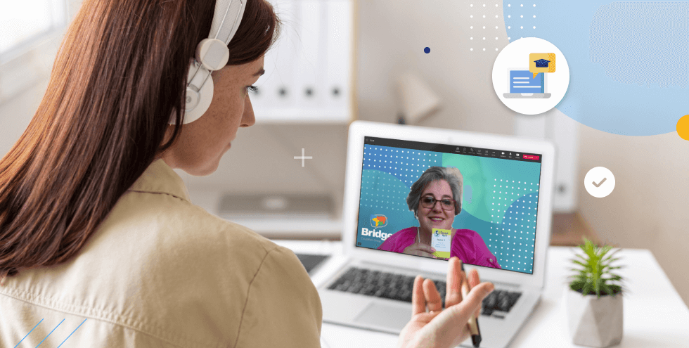 A woman wearing headphones participates in a virtual lesson with a Bridge Global Teacher displayed on her laptop screen. 