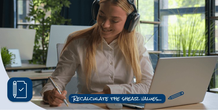 Persona con audífonos trabajando en su laptop y escribiendo notas técnicas en un entorno laboral.