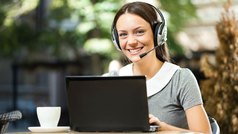 A young woman with headset on her laptop.