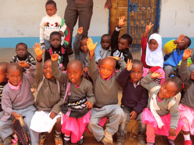 Lindsay's class of ESL students in Tanzania, raising their hands