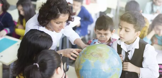 Teacher with students looking at globe