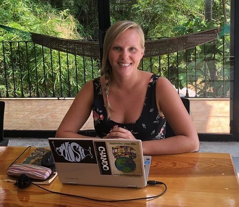 digital nomad and teacherpreneur Rachel Story sitting at a table outside with her laptop.
