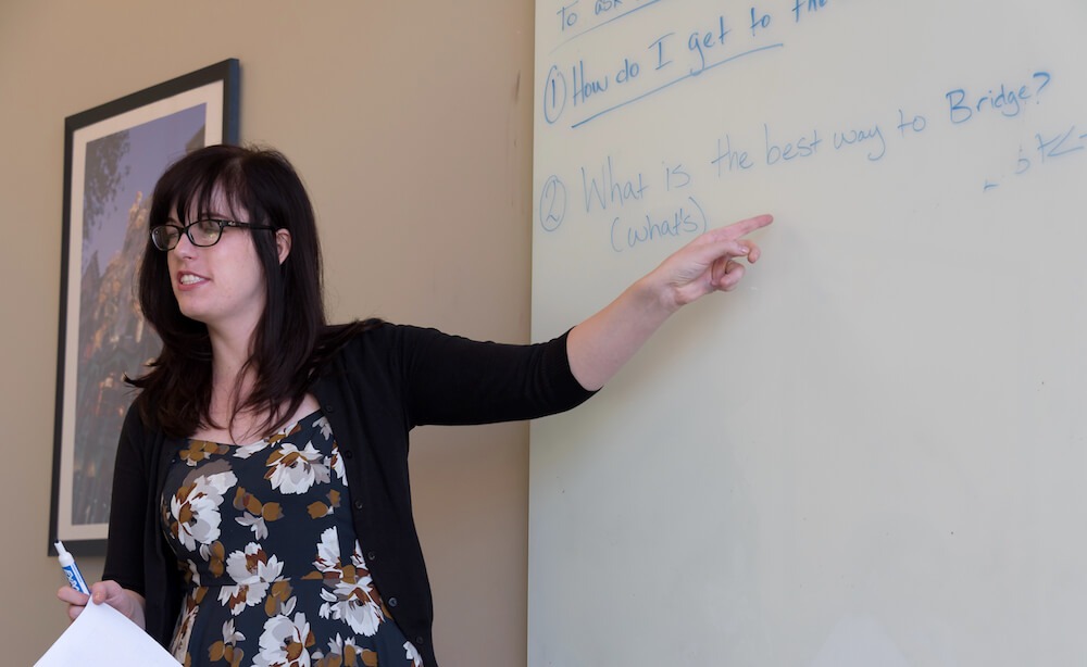 an ESL teacher pointing to a question on a whiteboard.