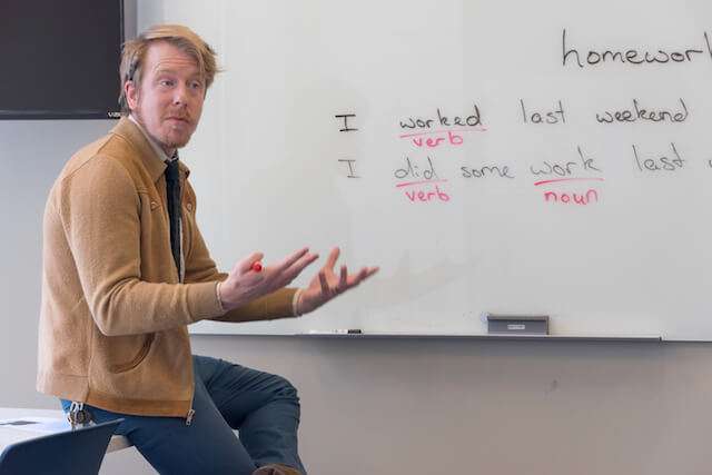 teacher in front of whiteboard with lesson on it