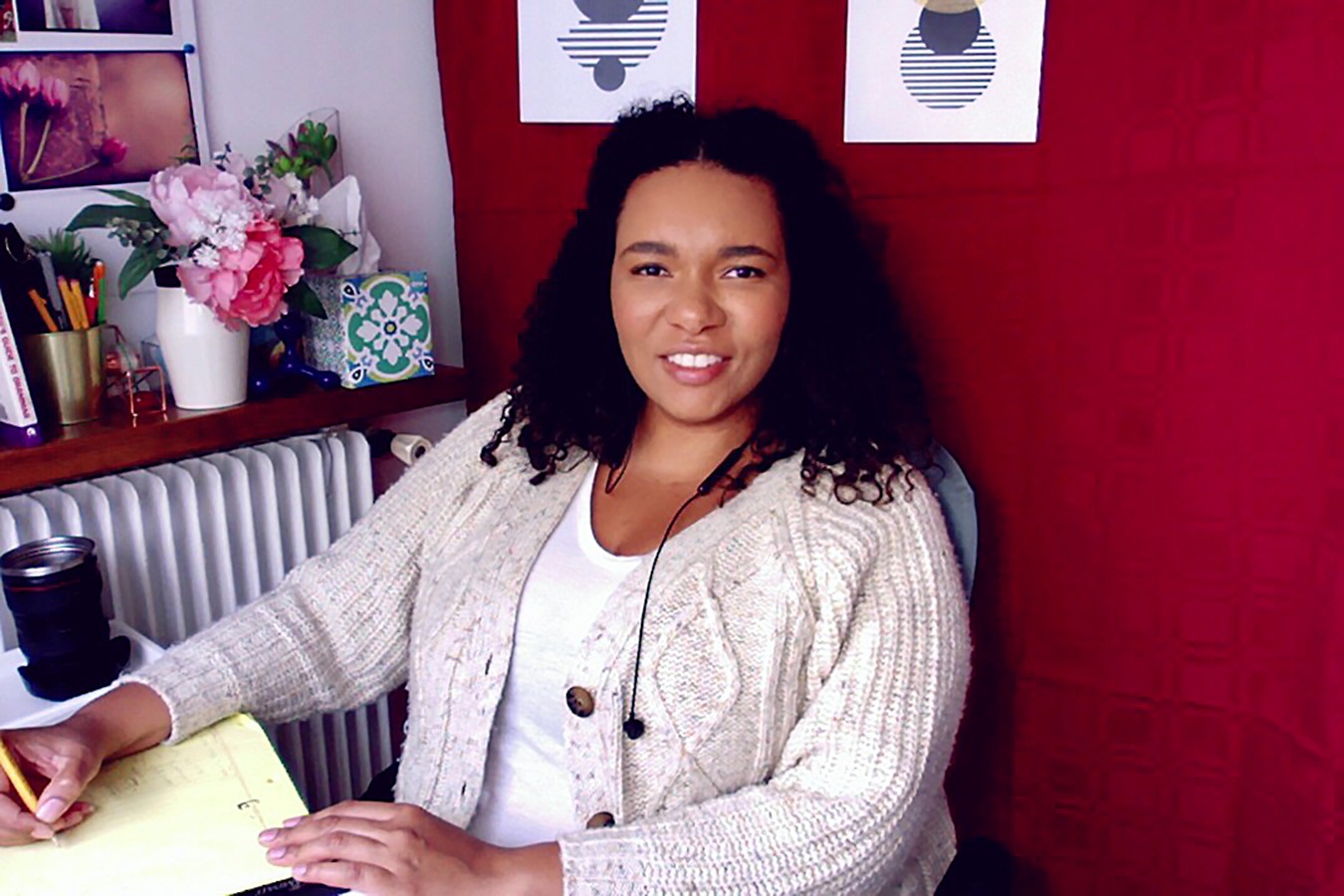 An image of a teacher named Sophia sitting at a desk, writing on a notepad