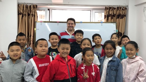 Mark Lee, who teaches and runs an EFL school in China, posing with a group of students.