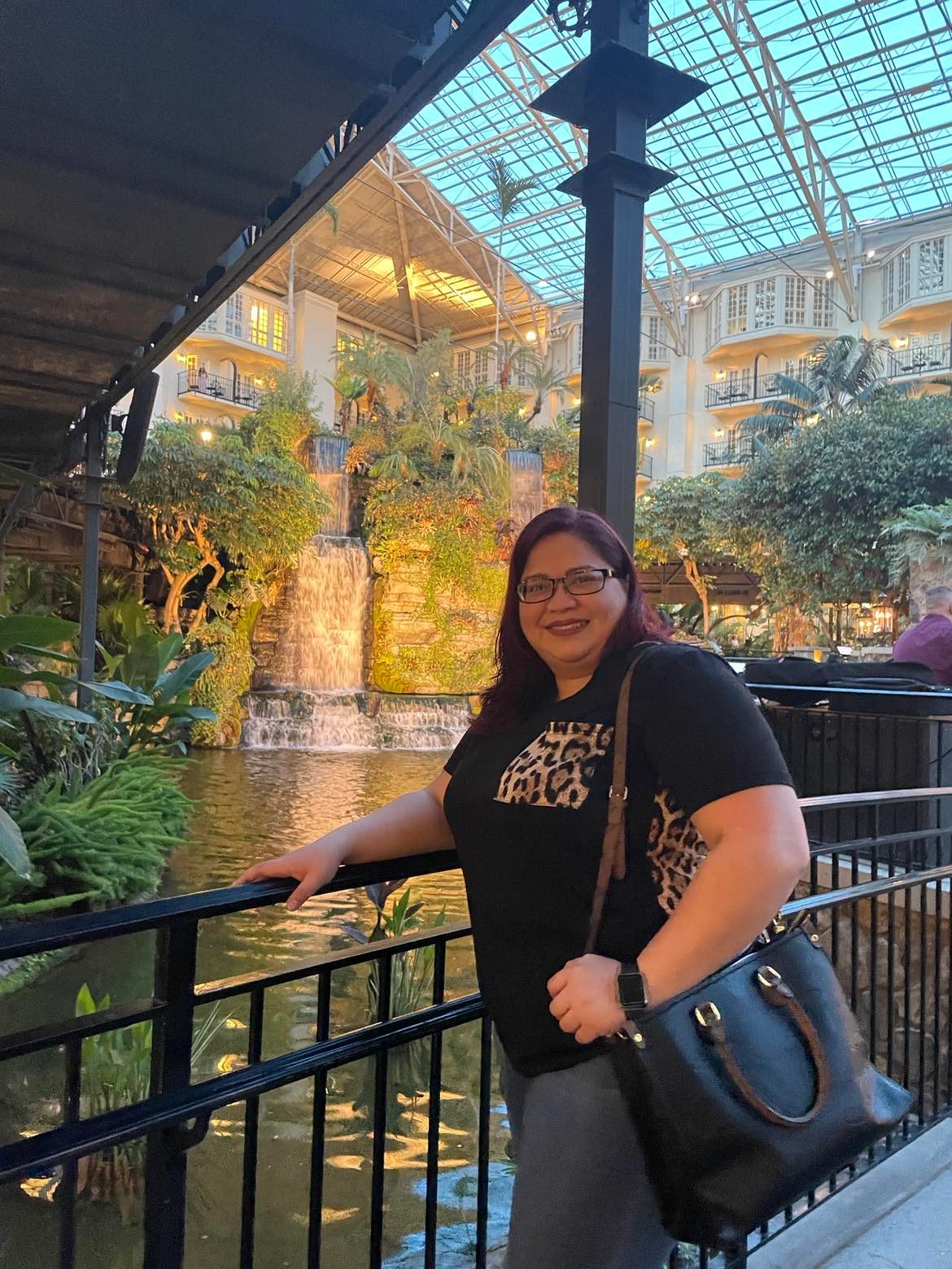 Angie Joy posing in front of an indoor water feature while traveling in Nashville.