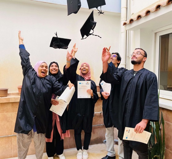 Bridge graduates wearing their graduation gowns and holding their certificates
