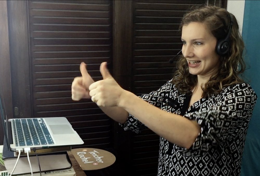 an online English teacher giving her learners a thumbs up.