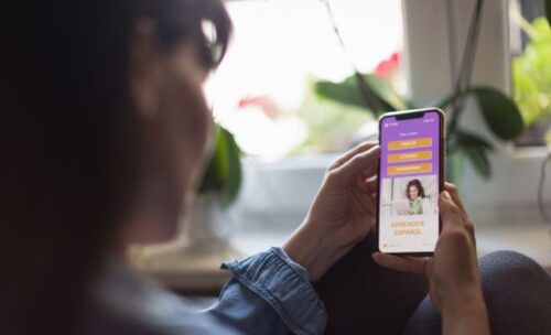 female student looks at her phone screen, which shows a mobile learning app.