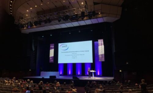 IATELF plenary presenter Ofelia Garcia stands on the main stage, speaking about viewing bilingualism and multilingualism through the lens of translanguaging.