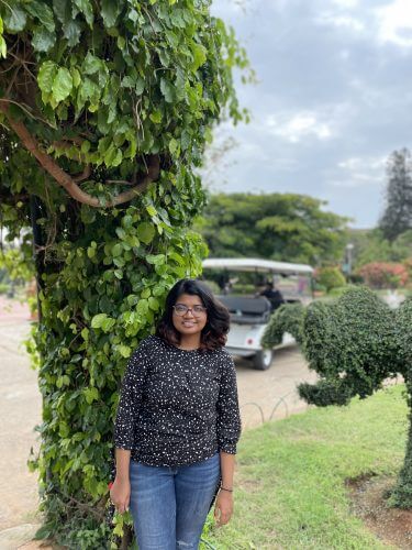 The interviewee stands in front of a tree at Brindavan Gardens in India.