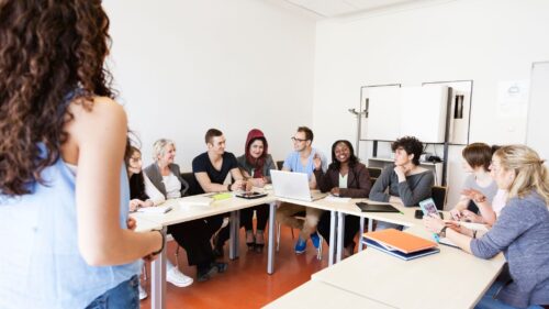 a teacher interacting with students at a conference table.