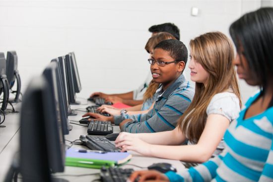 young students taking a test online in a computer lab.