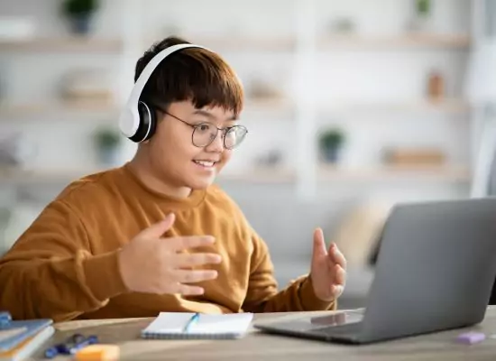 a young teen gesturing and smiling during an online ESL game activity.