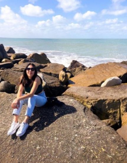 Bridge alumni, Celeste, sitting on a rock in front of the ocean in Argentina