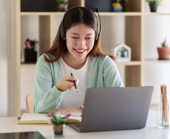 a woman smiles and gestures at her laptop.