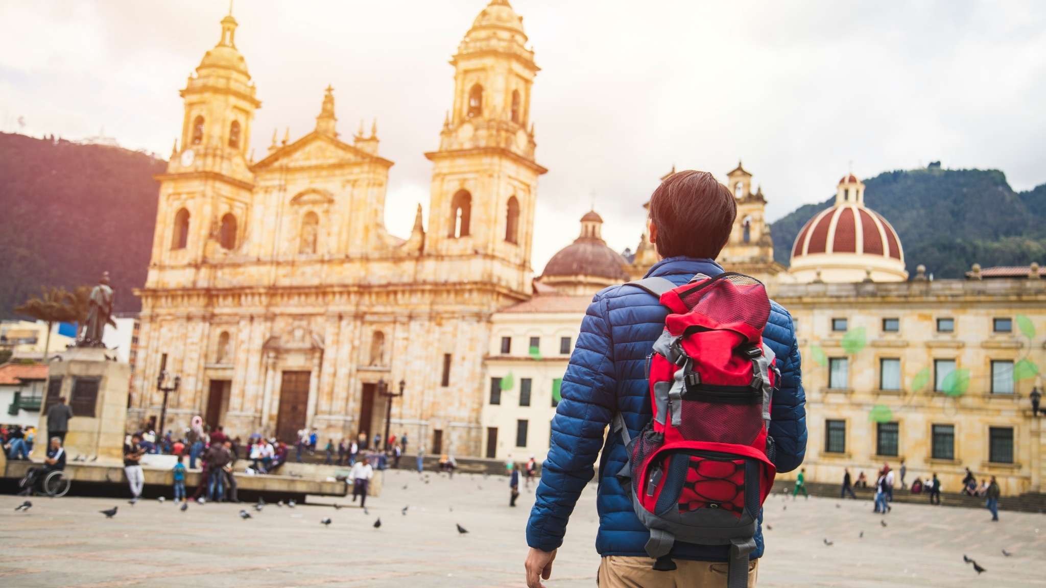 Young man traveling in Bogota, Colombia. Plaza de Bolívar, La Candelaria neighborhood. Taking some photos with the Catedral Primada.