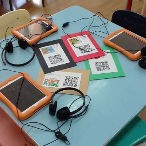 a desk with student tablets and headphones with stories that have QR codes.