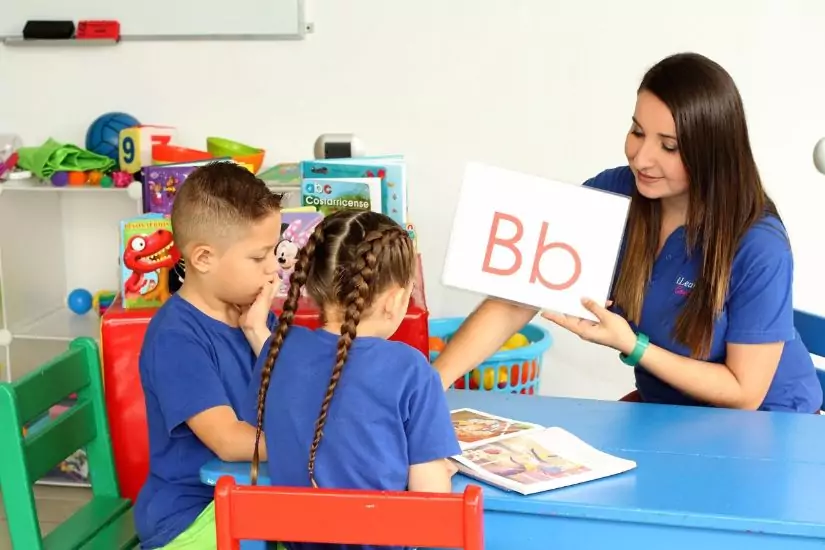 a teacher showing letters to her young students