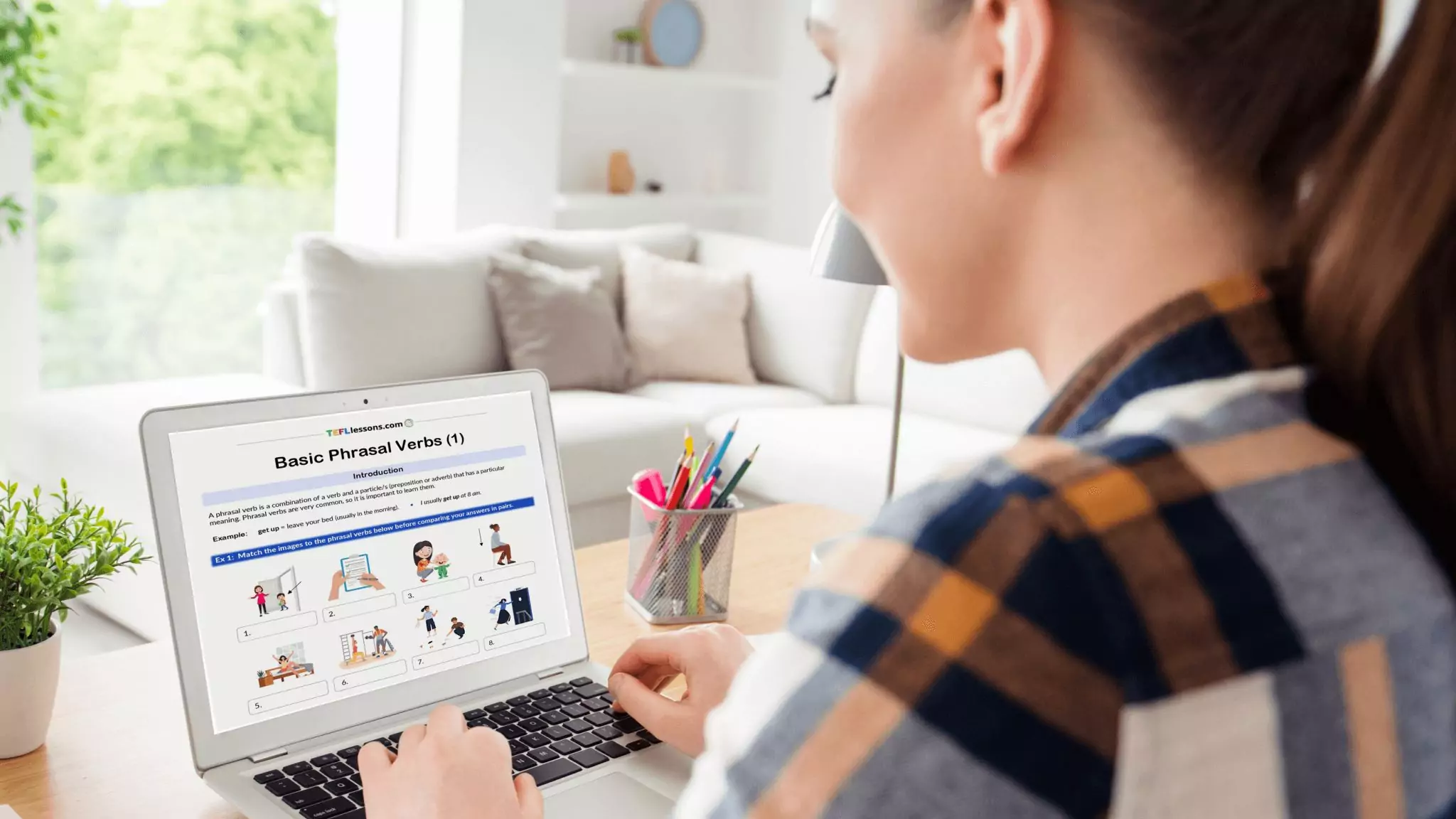 a woman looking at a basic phrasal verbs activity on her laptop screen.