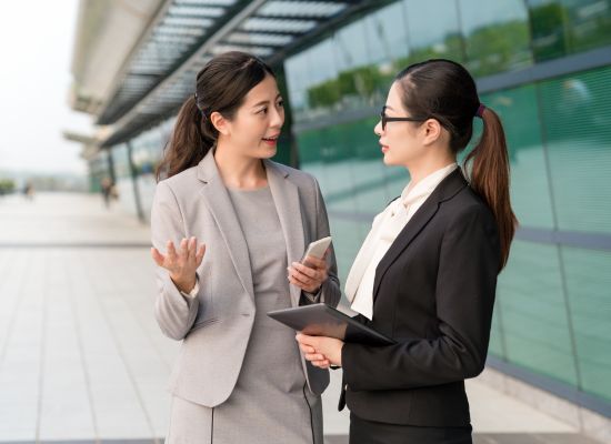 two women talk outside their office