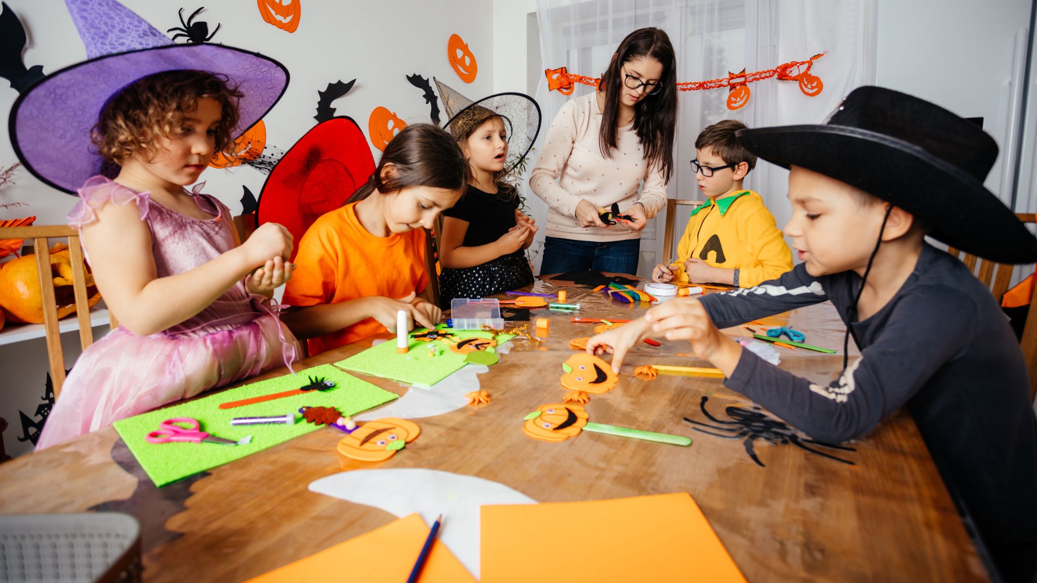 young students in costumes working on Halloween crafts