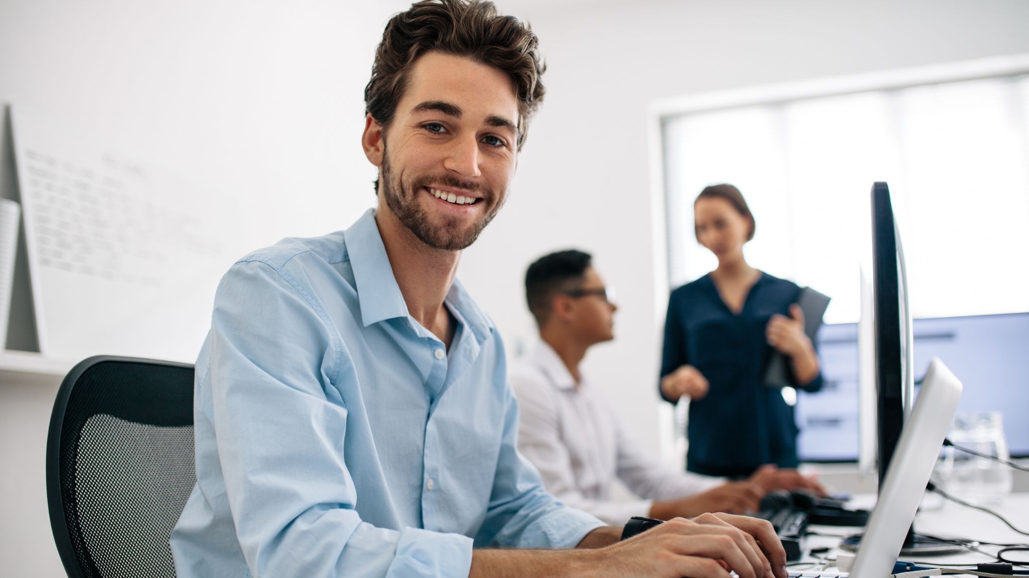 a young professional smiling in front of his laptop