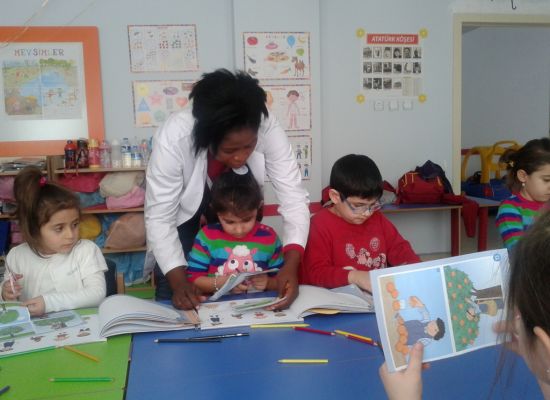 An image of a teacher helping students put together a story book