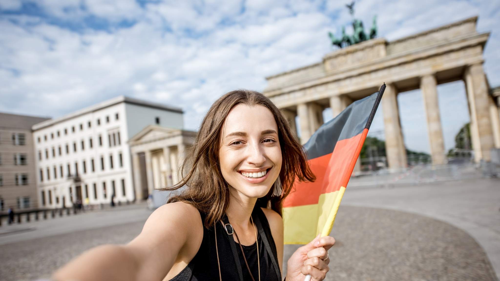 An image of a woman holding a German flag with German landmarks in the background