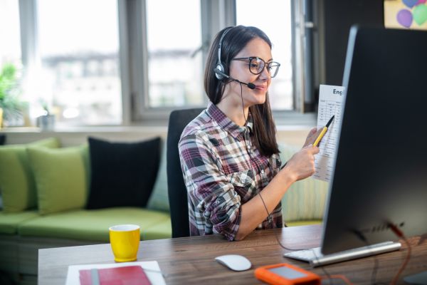 An image of a woman sitting at a desk teaching English online