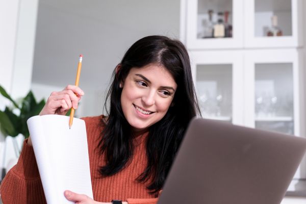 An image of a woman pointing to a notepad while teaching English online