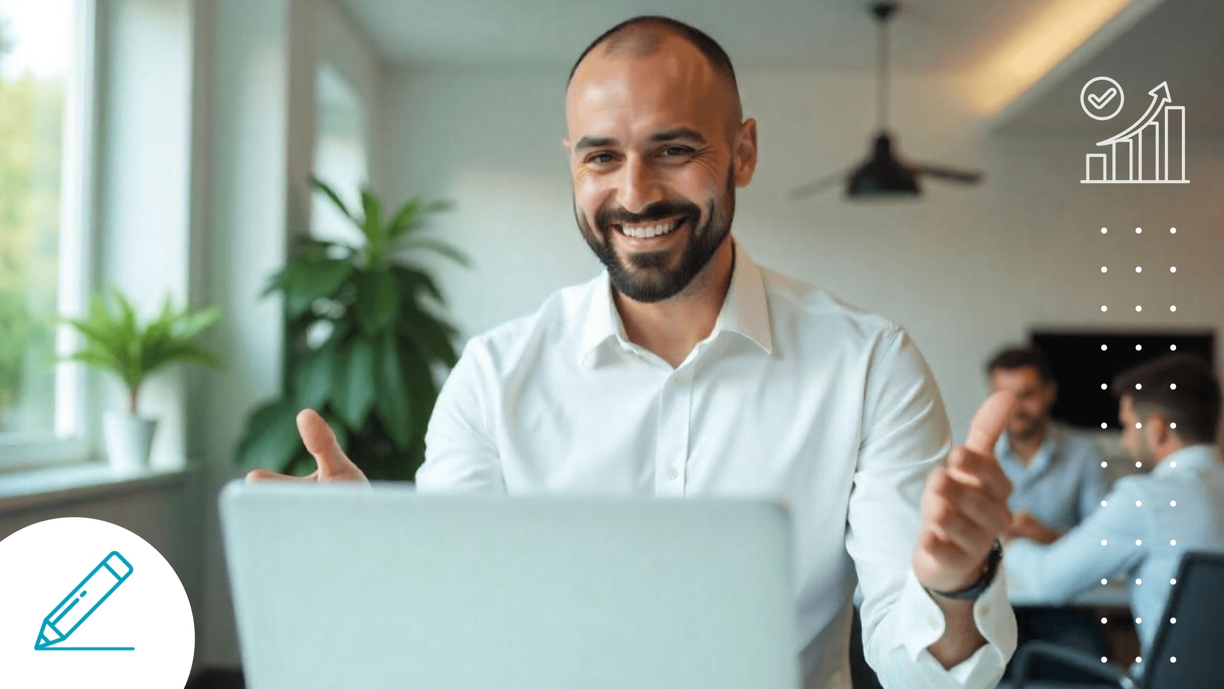 Smiling man in a white shirt engaged in a video call, gesturing while speaking. In the background, two colleagues are having a conversation in a modern office.