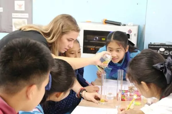 An image of a BFITS science teacher working with a group of students on an experiment in the classroom