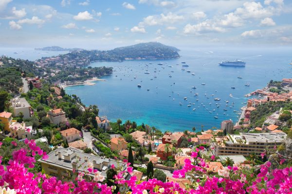 An image of French Riviera, the Cote d'Azur, with a view of the sea and pink flowers in the foreground