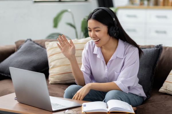 An image of a woman learning virtually on a laptop while sitting on a couch