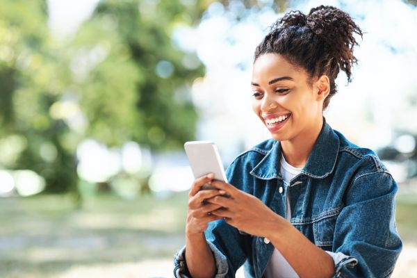 An image of a smiling girl using a speaking app on her smartphone to practice speaking English