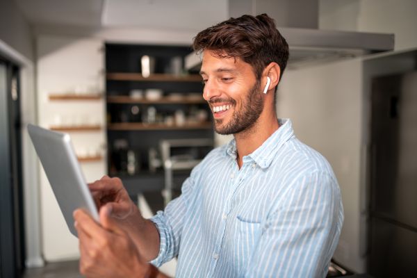 An image of a smiling man using an English speaking app on his tablet