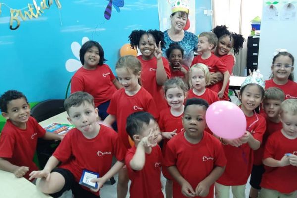 An image of an English teacher who is a Bridge TEFL graduate smiling with her English students in Malaysia
