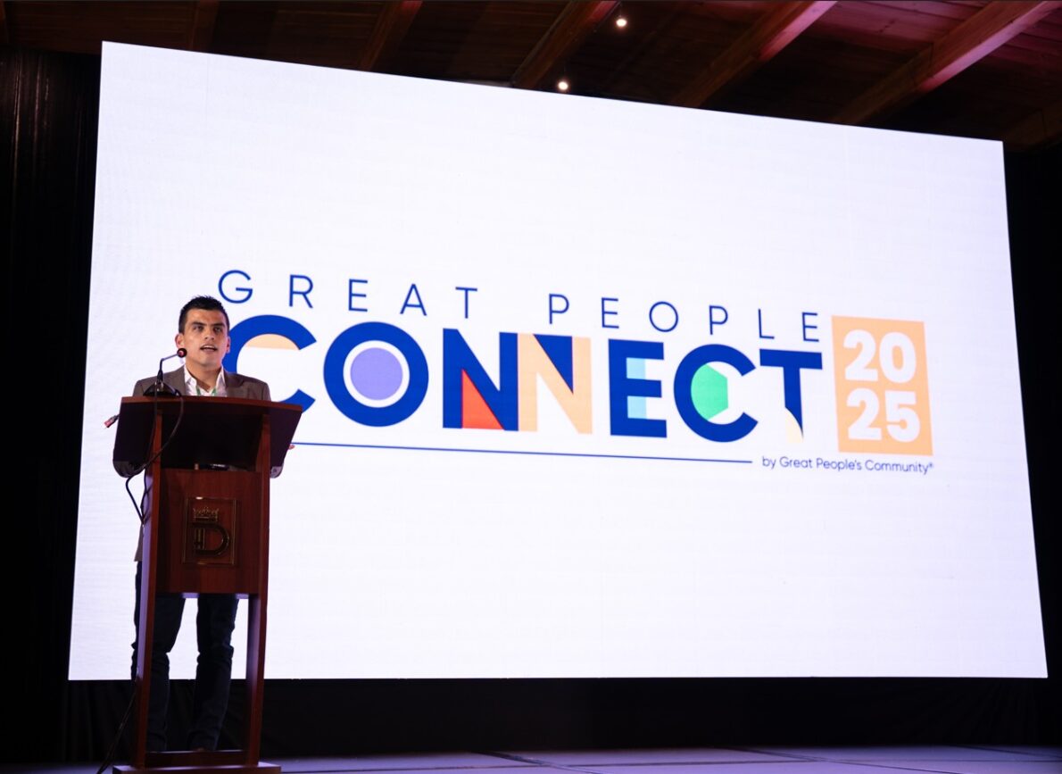 Orador en el escenario durante Great People Connect 2025 con pantalla gigante de fondo 