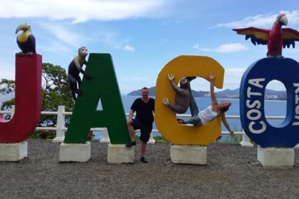 An image of Tom, a Bridge TEFL graduate, posing for a picture with the Jaco sign in Costa Rica