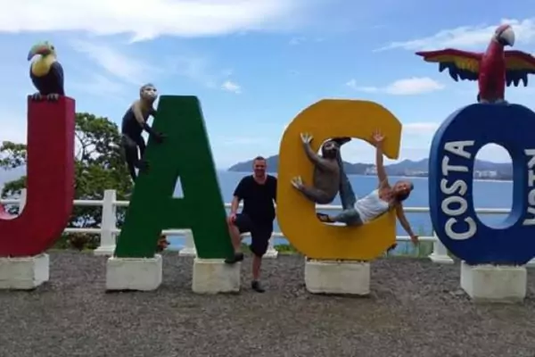 An image of Tom, a Bridge TEFL graduate, posing for a picture with the Jaco sign in Costa Rica