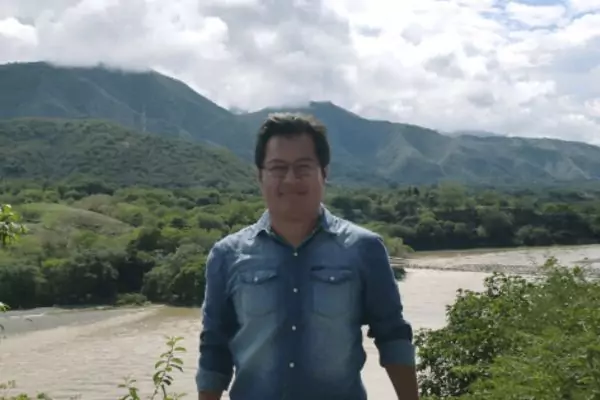 An image of a male English teacher with a river and mountains in the background