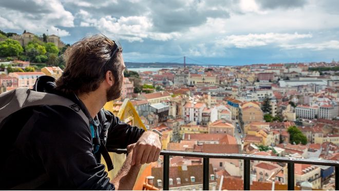 Man overlooking Lisbon’s cityscape with the 25 de Abril Bridge in the distance, a popular spot for teachers living and working in Portugal.