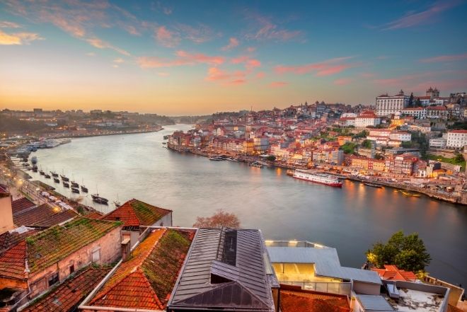 A panoramic view of Porto, Portugal, with the Douro River and colorful hillside buildings at sunset – a top location to teach English in Portugal.