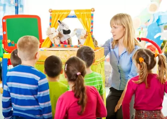 A teacher uses puppets to perform a skit with young learners.