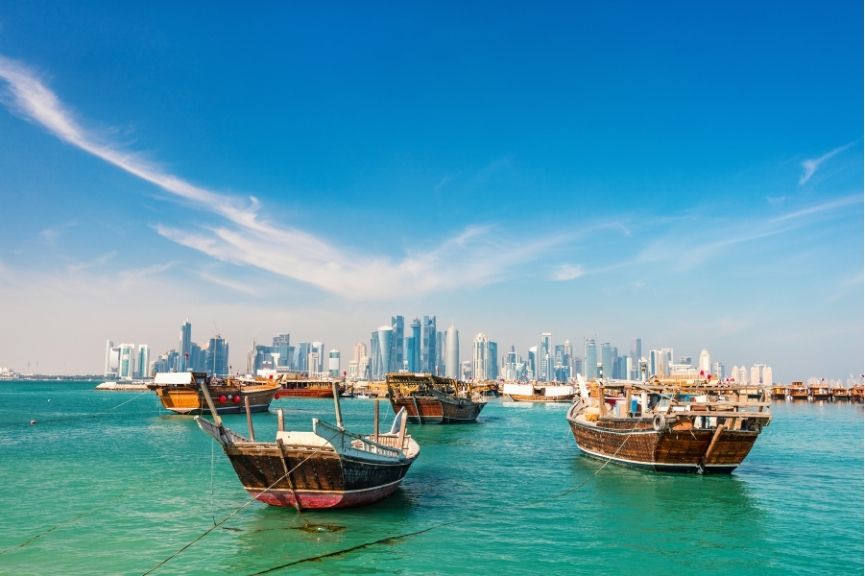 Waterfront in Doha, Qatar with traditional wooden small ships known as dhow and city skyline