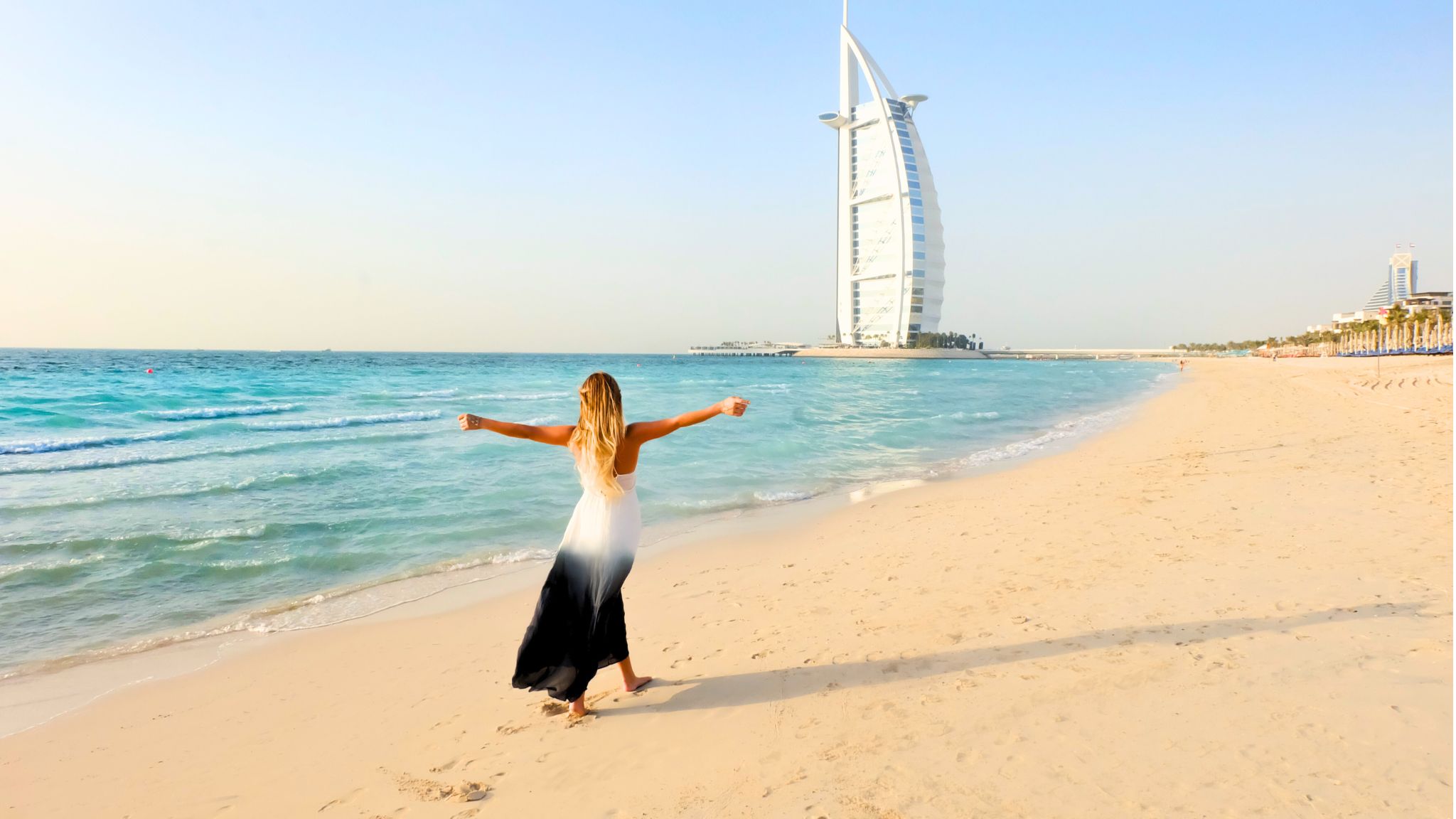 A Tourist on the beach with a view of the Burj Al Arab, in Dubai, one of the best destinations to teach English in the UAE.