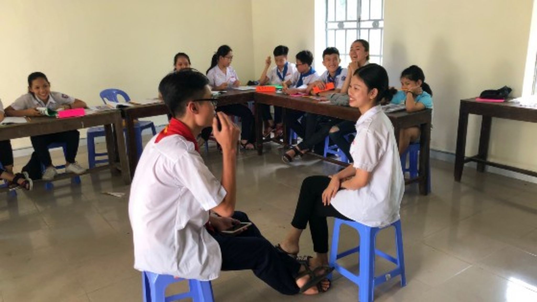 Two tenagers perform an icebreaker in class, in front of the group.